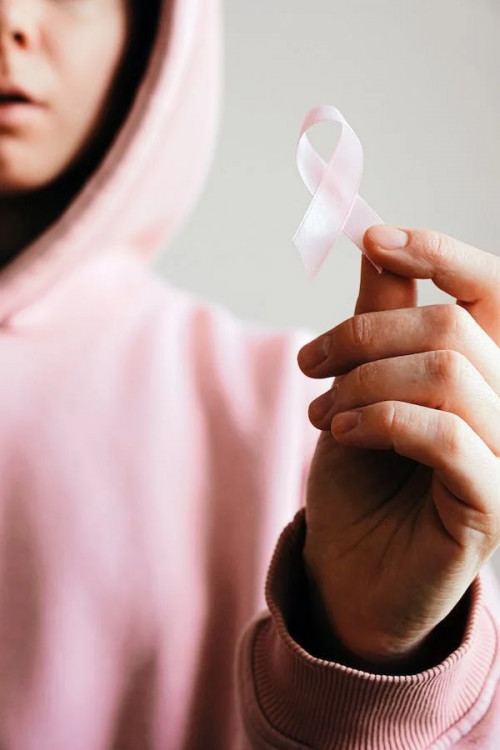 ilustrasi perempuan memegang pita pink logo kanker serviks, foto: pexels