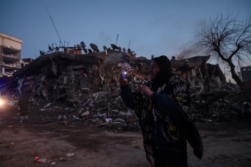 Warga berjalan di dekat bangunan yang hancur akibat gempa di Kahramanmaras, Turki. Foto: AFP
