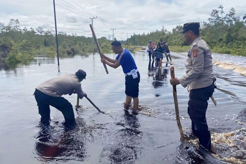 Petugas Polsek Timpah membuat tanda untuk pembatas jalan yang berlubang akibat banjir, Jumat (31/3/2023). (ANTARA/HO-Polsek Timpah)