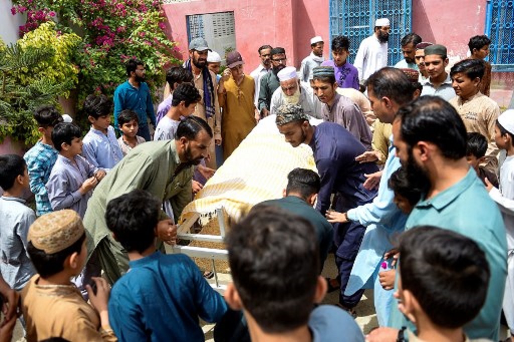 Warga mengangkat salah satu korban tewas terhimpit dalam pembagian donasi makanan di Karachi, Pakistan, 1 April 2023. (Rizwan TABASSUM / AFP)