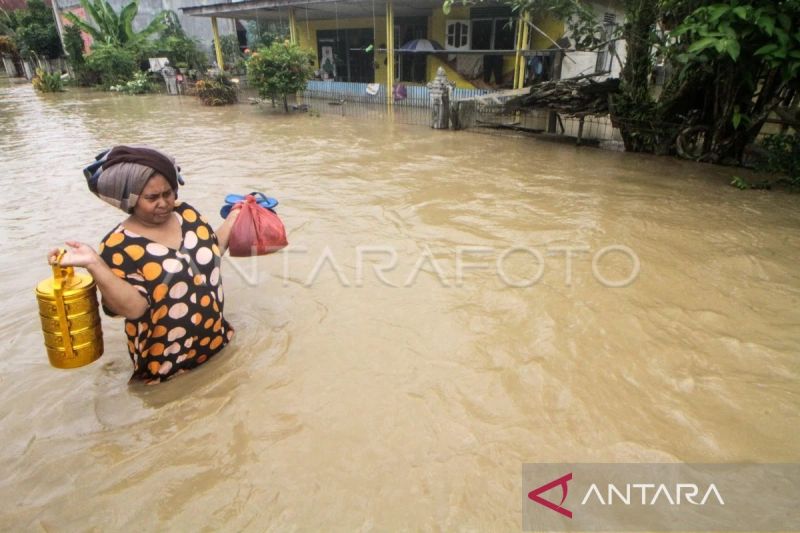 Warga menerobos banjir saat keluar dari permukiman di Desa Alue Thoe, Kecamatan Matang Kuli, Aceh Utara, Aceh, Senin, 9 Oktober 2023. Antara/Rahmad