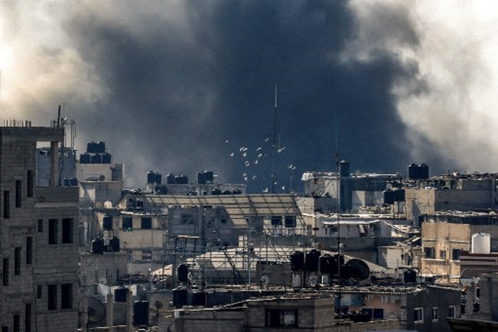 Asap hitam terlihat dari lokasi serangan Israel di Rafah antara Jalur Gaza dan Mesir, 12 Desember 2023. (MAHMUD HAMS / AFP)