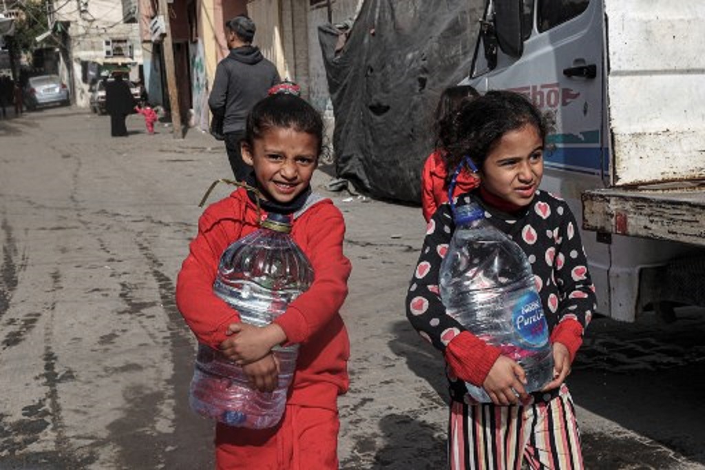 Anak-anak membawa air di Rafah, Jalur Gaza, 17 Maret 2024. (SAID KHATIB / AFP)