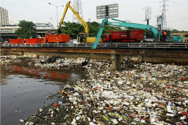 Pekerja menggunakan alat berat untuk mengangkat sampah yang tersangkut dalam jembatan saat kegiatan bersih-bersih sampah di Sungai Banjir Kanal Barat (BKB), Jakarta, Kamis (14/11). Foto: Antara/Dhoni Setiawan.