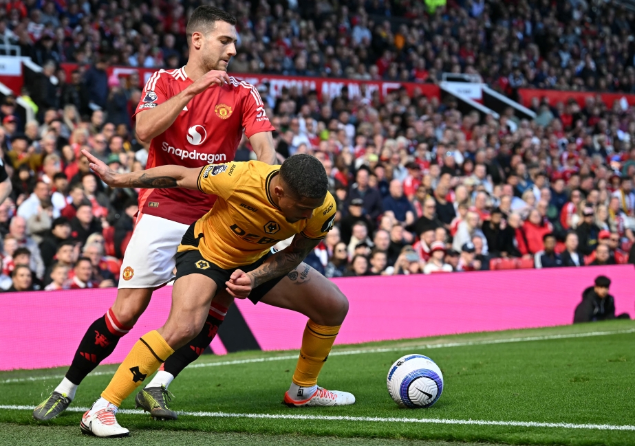 Bek Manchester United, Diogo Dalot, mencoba merebut bola dari gelandang Wolverhampton Wanderers, Joao Gomes (AFP/Paul Ellis)