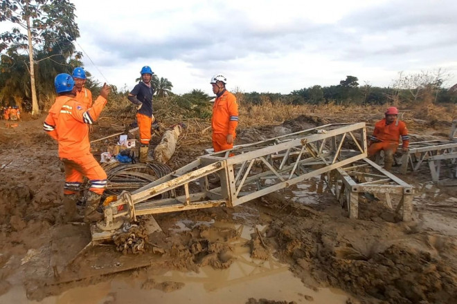 Di tengah medan yang berlumpur, petugas PLN melakukan perakitan tower darurat di jalur transmisi Langsa-Pangkalan Brandan.