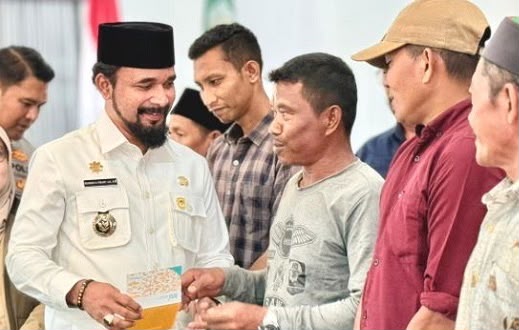 Bupati Aceh Timur Iskandar Usman Alfarlaky memberikan buku tabungan berisi bantuan sosial bagi warga terdampak bencana. Foto: dok. Satgas PRR/Pemkab Aceh Timur