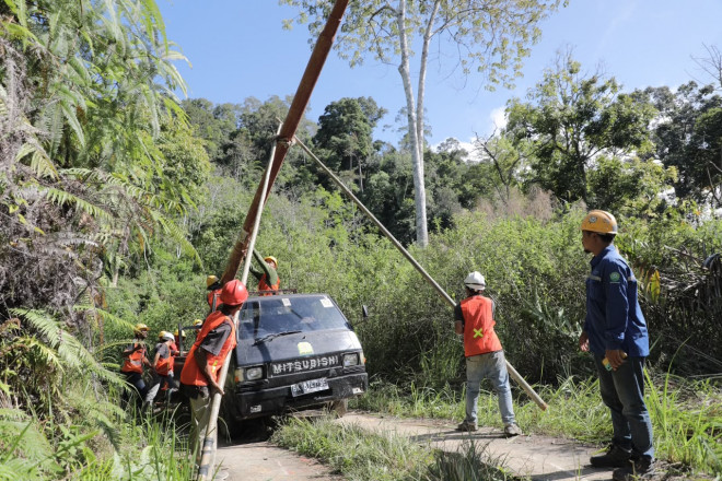 Petugas PLN memobilisasi tiang listrik melalui medan berat untuk menghadirkan listrik di Desa Patialo. Foto: PLN