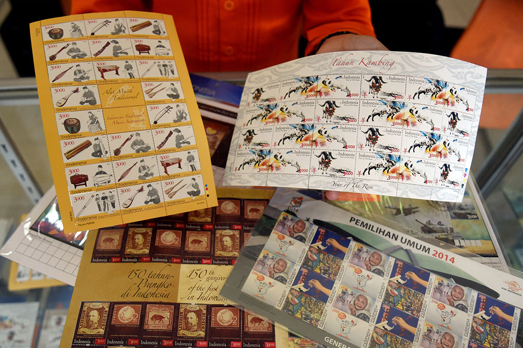Petugas menunjukkan dua prangko seri Shio Tahun Kambing dan alat musik tradisional yang diterbitkan oleh PT Pos Indonesia di Jakarta, Selasa (10/3).