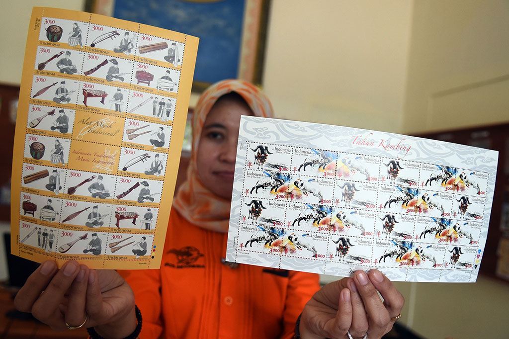 Petugas menunjukkan dua prangko seri Shio Tahun Kambing dan alat musik tradisional yang diterbitkan oleh PT Pos Indonesia di Jakarta, Selasa (10/3).