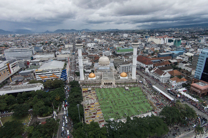 Warga bermain di Alun-alun Kota Bandung, Jawa Barat, Sabtu (25/4). Kawasan seluas 4.000 meter persegi yang menyuguhkan hamparan rumput sintetis tersebut terletak di depan Masjid Raya Bandung dan menjadi destinasi wisata alternatif yang ramai dikunjungi masyarakat pada akhir pekan. 