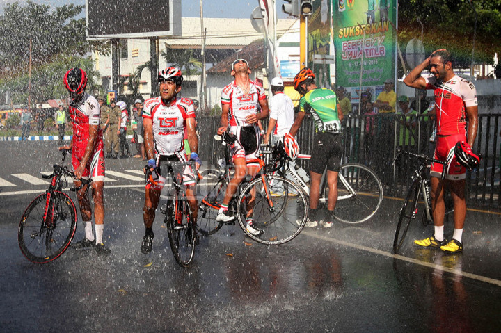 Peserta International Tour de Banyuwangi Ijen (ITdBI) 2015 mendinginkan tubuh dengan air seusai menyelesaikan etape pertama dengan rute sejauh 167 kilometer dari Glenmore ke Taman Blambangan, Banyuwangi, Jawa Timur, Rabu (6/5/2015).