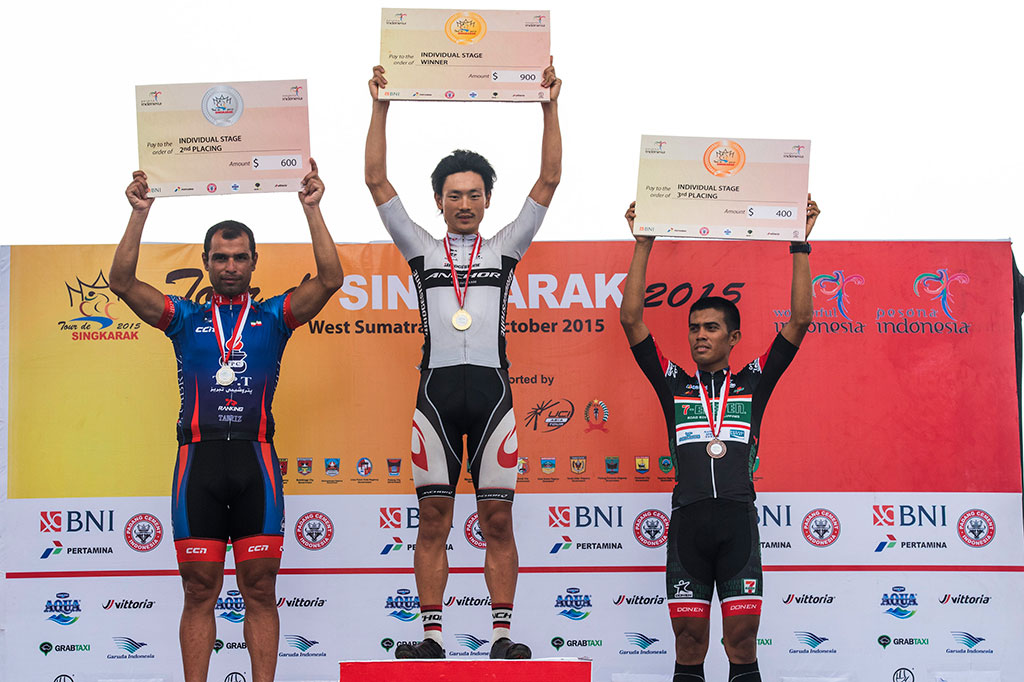 Pebalap sepeda Bridgestone Anchor Cycling Team Sho Hatsuyama (tengah) didampingi Tabriz Petrochemical Team Mehdi Sohrabi (kiri) dan Seven Eleven Roadbike Philippines Marcelo Felipe (kanan) mengangkat tangan papan cek uang saat prosesi penyerahan hadiah pada Tour De Singkarak etape kesembilan.