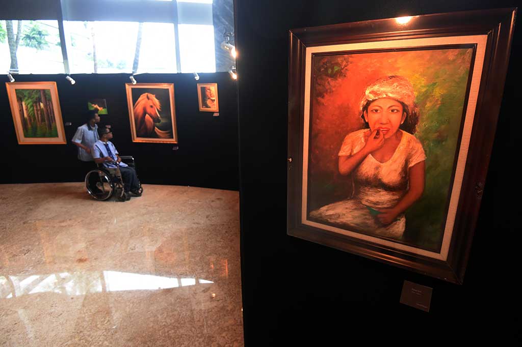 Pengunjung mengamati lukisan karya pelukis disabilitas.