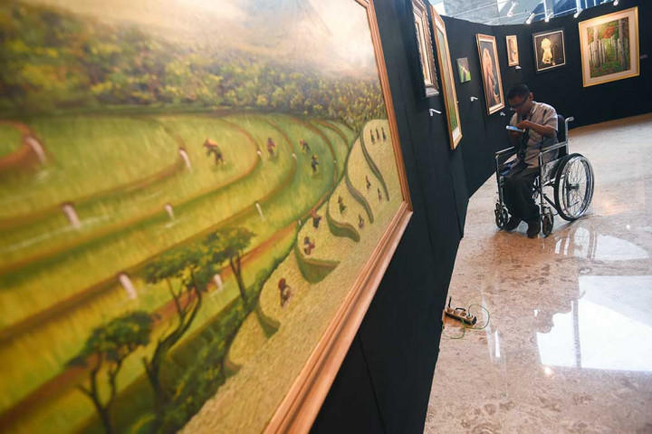 Pengunjung mengamati lukisan karya pelukis disabilitas.