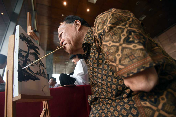 Pelukis Sayang Bangun menunjukkan kemampuan pada pameran lukisan karya disabilitas.