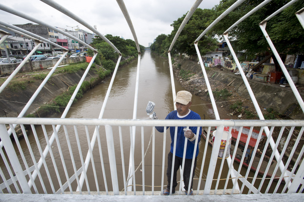 Pekerja tengah menyelesaikan pembangunan JPO di atas Sungai Ciliwung di kawasan Manggarai.