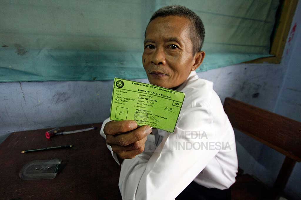 Moh. Muhlasin (52), salah satu peserta Ujian Nasional (UN) kesetaraan Paket C tertua di Kota Depok, menunjukkan kartu peserta UN sebelum melaksanakan ujian di SMA Al-Muhajirin, Depok, Jawa Barat, Selasa (5/4/2016). 