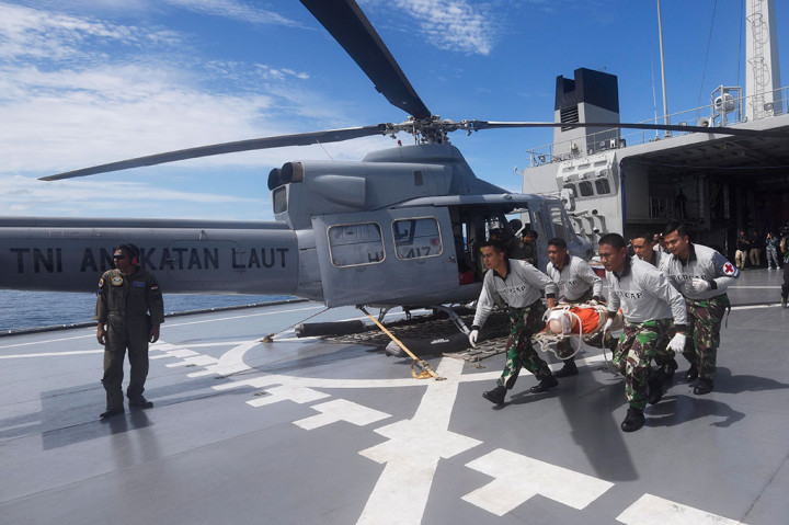 Anggota TNI Angkatan Laut membawa korban menuju helikopter.
