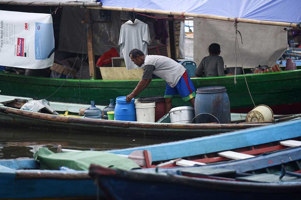 Seorang warga menata air bersih di atas perahu mereka.