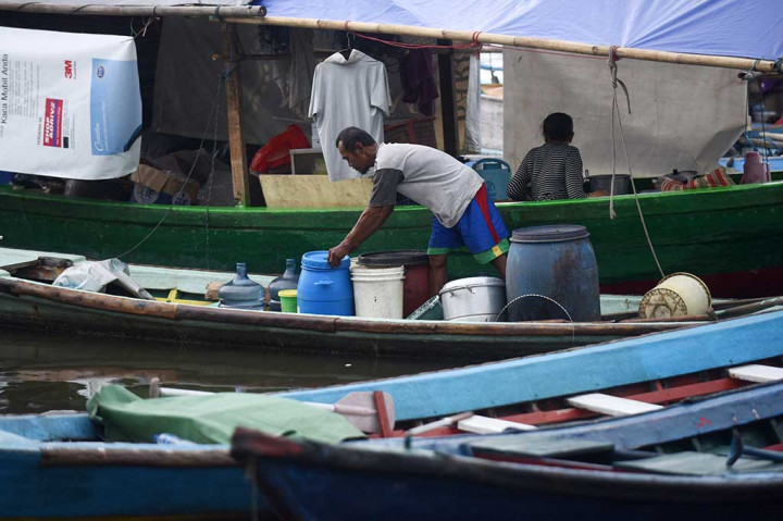 Seorang warga menata air bersih di atas perahu mereka.