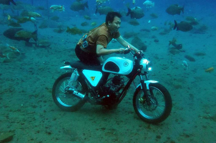 Seorang pria berfoto di atas motor di dalam Kolam Umbul Ponggok