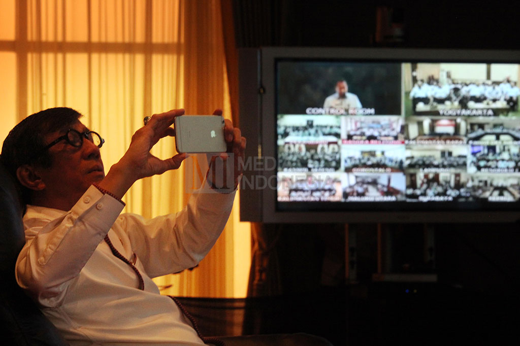 Yasonna Laoly mengabadikan gambar dengan smartphone saat teleconfrence dengan kepala kantor imigrasi seluruh Indonesia.