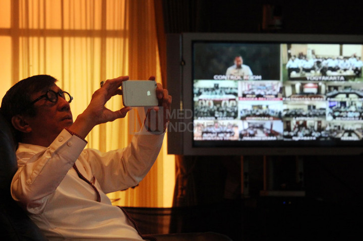 Yasonna Laoly mengabadikan gambar dengan smartphone saat teleconfrence dengan kepala kantor imigrasi seluruh Indonesia.