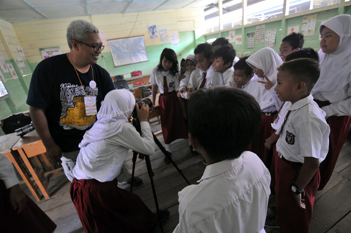 Relawan Kelas Inspirasi Jambi yang juga pegiat fotografi Riko Mappedeceng (kiri) mengajarkan dasar-dasar fotografi kepada pelajar SDN 68 Kota Jambi di Danau Sipin, Jambi, Senin (2/5). Dalam rangka memperingati Hari Pendidikan Nasional, puluhan relawan serentak memberikan pengajaran di 25 SDN pinggiran di daerah itu melalui program Kelas Inspirasi Jambi. ANTARA/Wahdi Septiawan