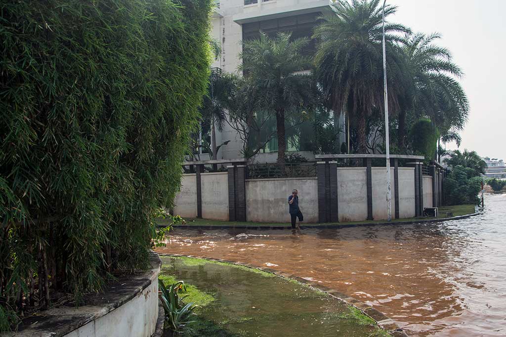 Warga berjalan di genangan air kawasan perumahan Pantai Mutiara.