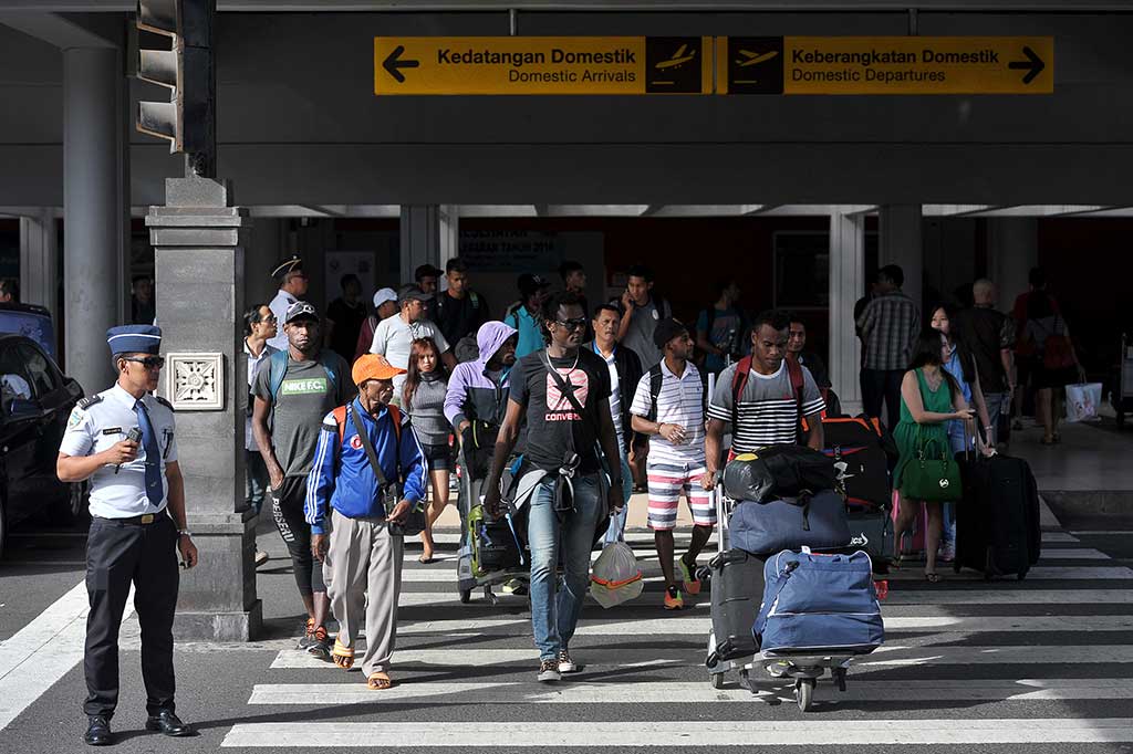 Petugas bandara mengawasi penumpang yang baru tiba di terminal kedatangan domestik Bandara Ngurah Rai.