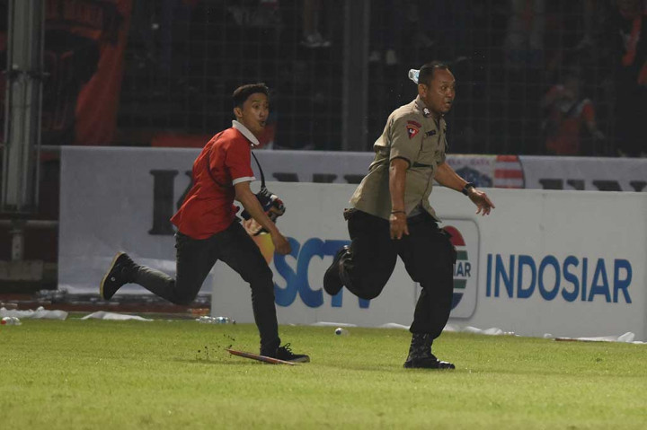 Suporter Persija Jakarta mengejar petugas kepolisian ketika terlibat kericuhan.