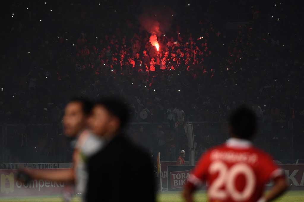 Suporter Persija Jakarta menyalakan flare.