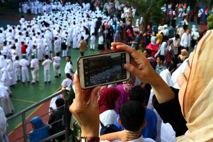 Orang tua murid mengabadikan kegiatan anaknya di hari pertama masuk sekolah di Madrasah Ibtidaiyah Pembangunan, Ciputat, Tangerang Selatan, Banten. ANTARA/Muhammad Iqbal