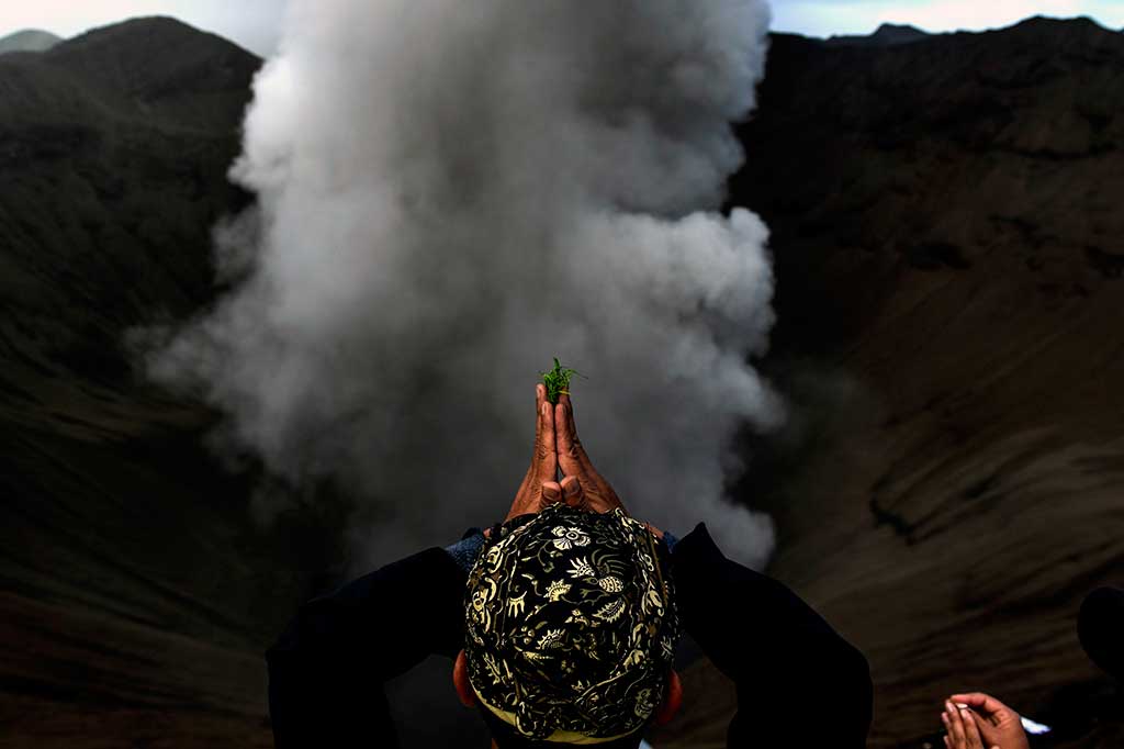 Warga Suku Tengger berdoa ketika melarung sesajen ke kawah Gunung Bromo.