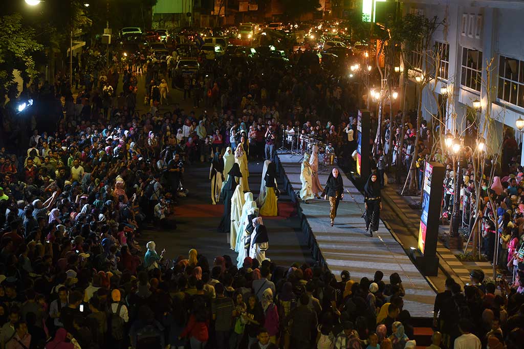Warga menyaksikan model yang memperagakan busana muslim saat digelar Fashion on the Street di Surabaya.