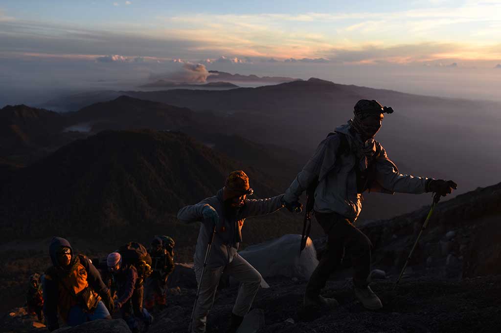 Pendaki mendaki Gunung Semeru dengan latar Gunung Bromo.