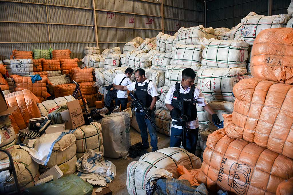 Petugas kepolisian berjaga di gudang penyimpanan pakaian impor bekas di kawasan Pulogebang.