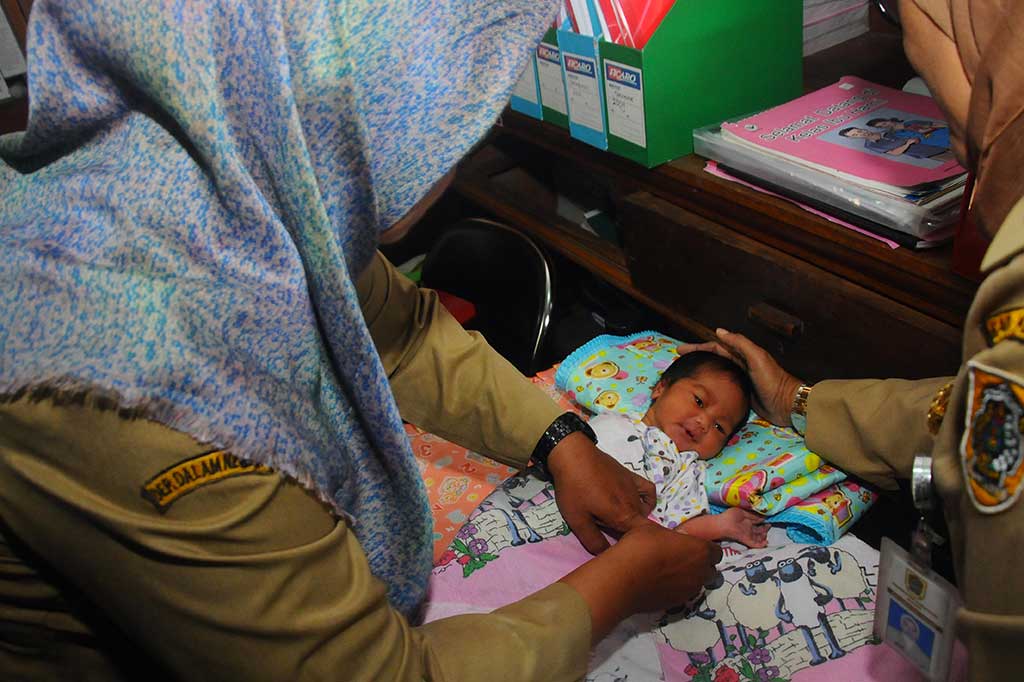 Petugas kesehatan menggantikan baju sang bayi di Puskesmas Pedan, Klaten, Jawa Tengah, Selasa (2/8/2016).