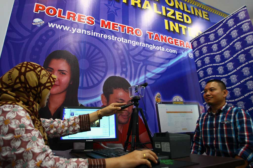 Petugas Kepolisian Satuan Penyelenggara Administrasi (Satpas) SIM Polres Metropolitan Tangerang mengambil foto warga pemohon perpanjangan SIM di Gerai SIM Alam Sutera, Serpong, Tangerang, Banten, Rabu (3/8/2016). 
