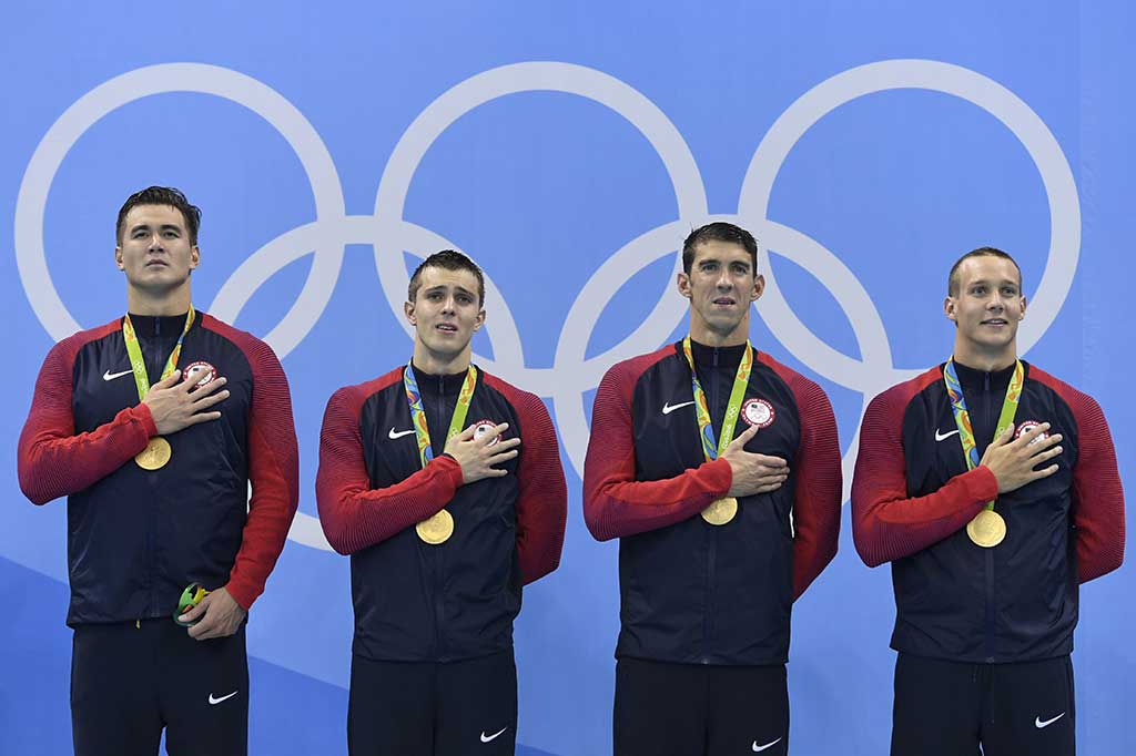Peranang AS (dari kiri) Nathan Adrian, Ryan Held, Michael Phelps dan Caeleb Dressel menyanyikan lagu kebangsaan usai pengalungan medali.