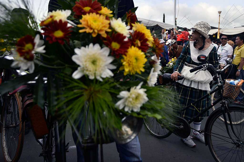 Anggota komunitas sepeda onthel menghias sepedanya dengan rangkaian bunga pada kegiatan parade Tomohon International Flower Festival (TIFF) 2016.