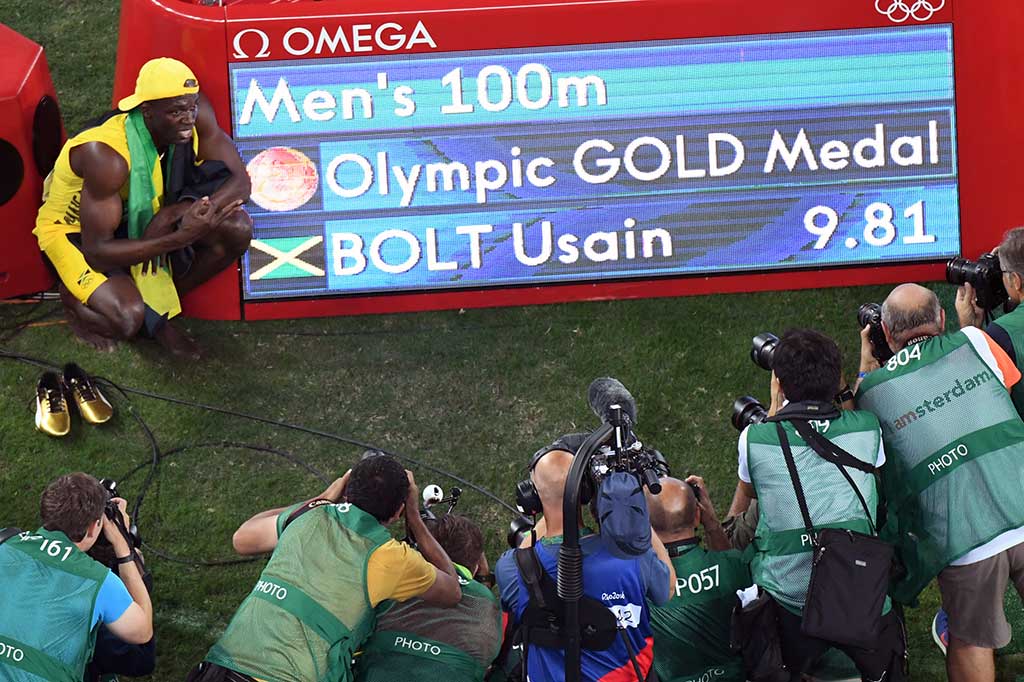 Bolt berpose di depan catatan waktu yang baru saja diraihnya.