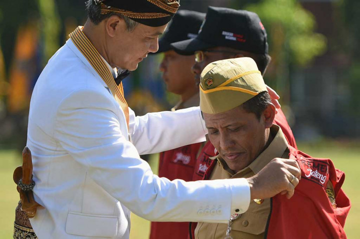 Ganjar Pranowo memakaikan rompi Gerakan Nasional Revolusi Mental kepada seorang PNS.