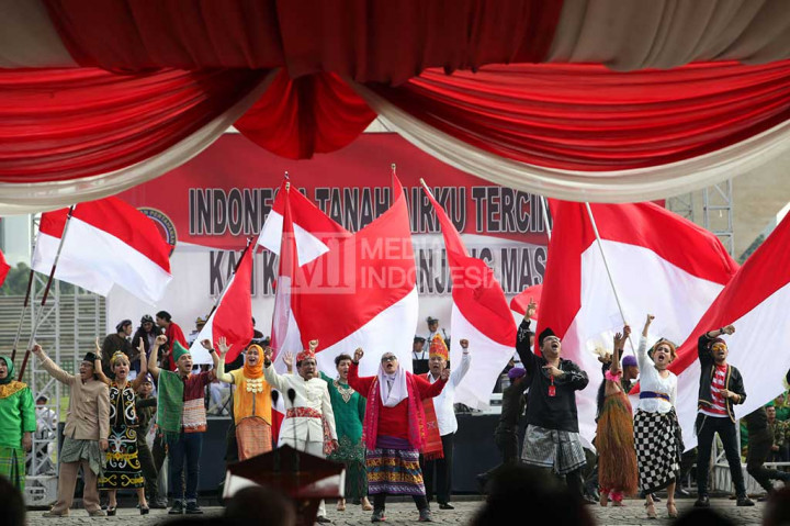 Peserta berpakaian adat menyanyikan Mars Bela Negara diiringi pembawa bendera.