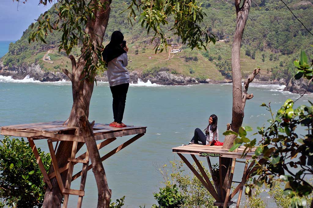 Wisatawan berfoto dengan latar pemandangan dari atas bukit di kawasan Pantai Watu Bale.