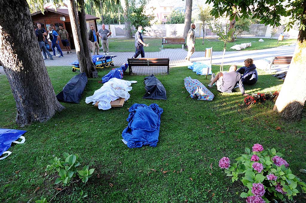 Para korban gempa di Amatrice tidur di rerumputan.