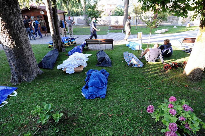 Para korban gempa di Amatrice tidur di rerumputan.