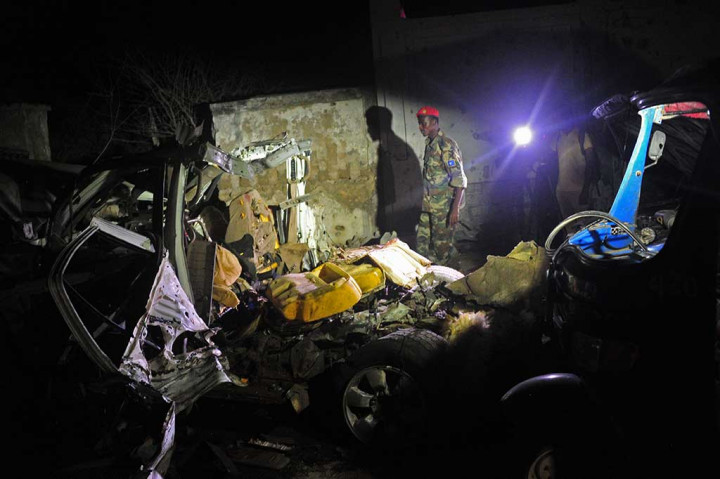 Tentara Somalia berada di dekat mobil yang hancur akibat serangan bom oleh Al Shabaab.