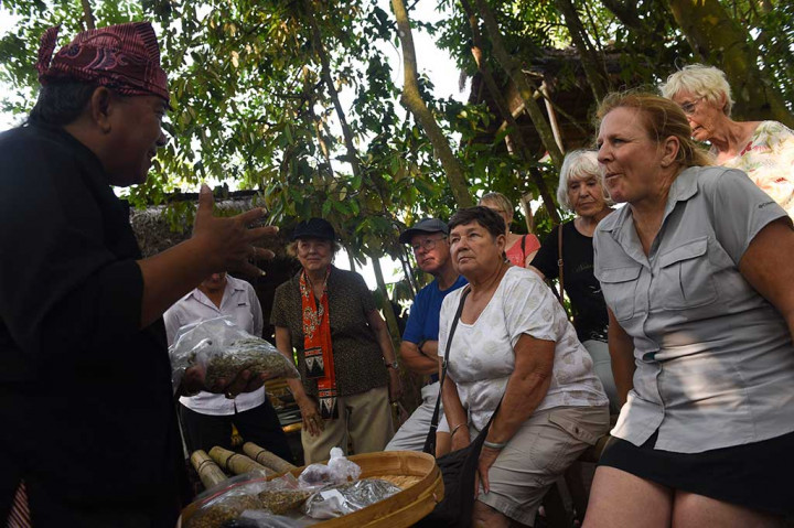 Wisatawan mancanegara mendengarkan penjelasan pemandu mengenai pembuatan kopi tradisional di Kampung Suku Osing, Banyuwangi.
